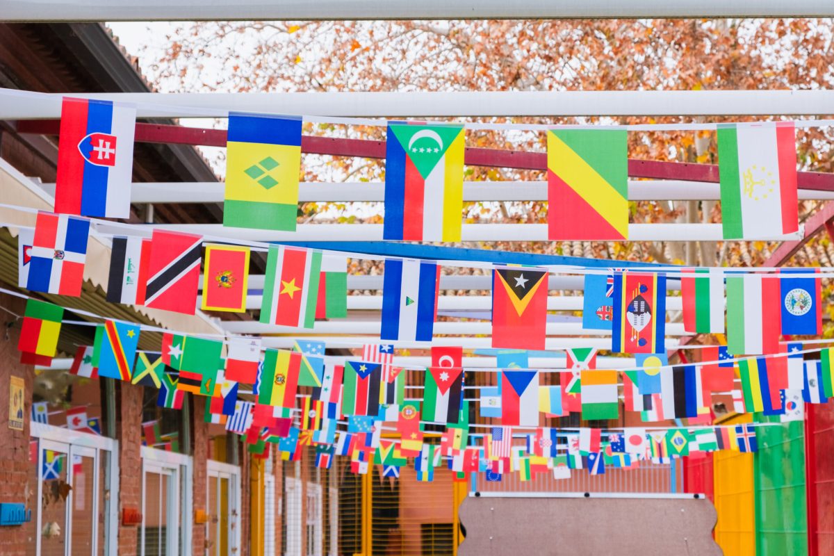 A variety of flags from many countries hang together in a children's playground as a sign of harmony.