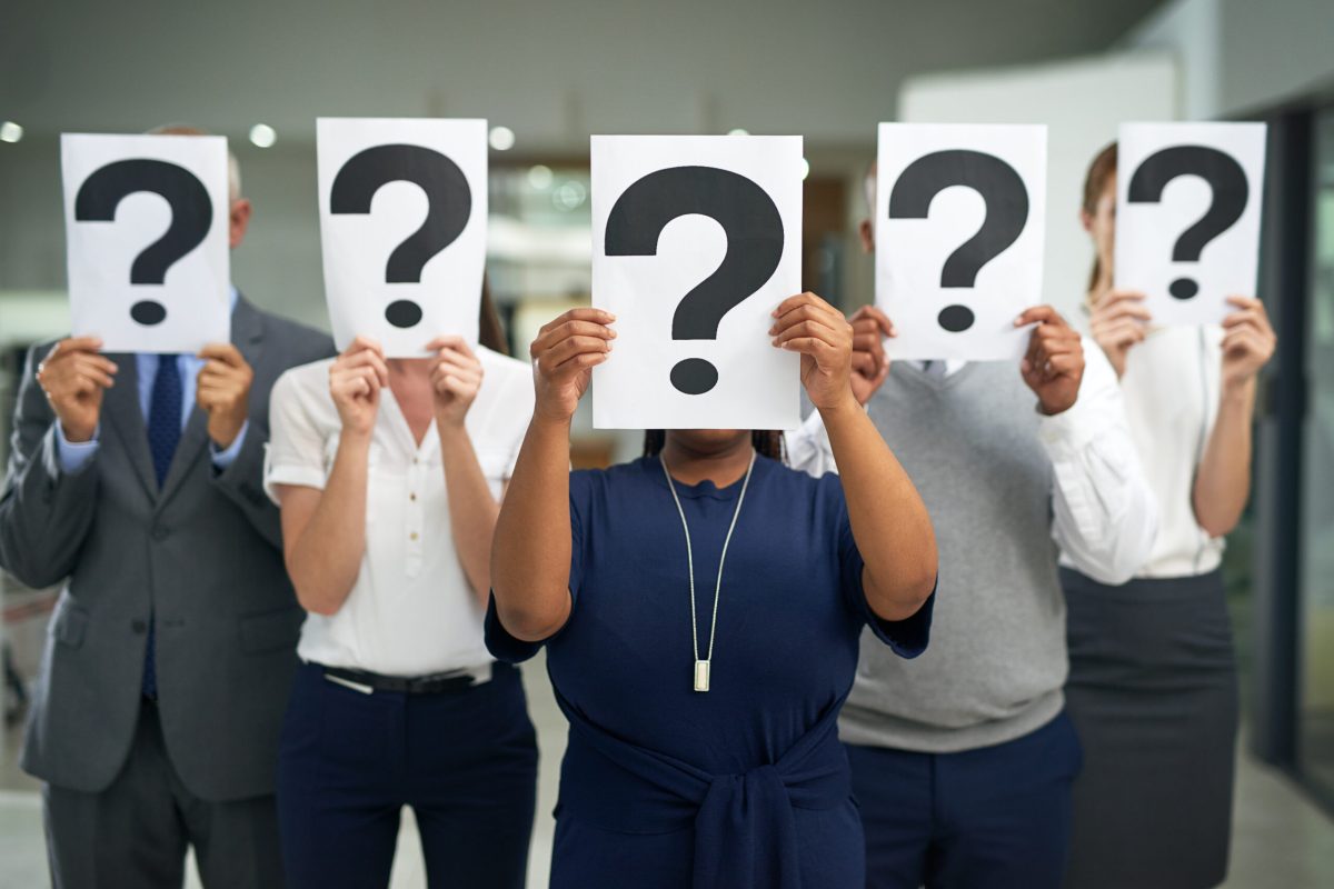 Shot of a group of businesspeople holding questions marks in front of their faces.